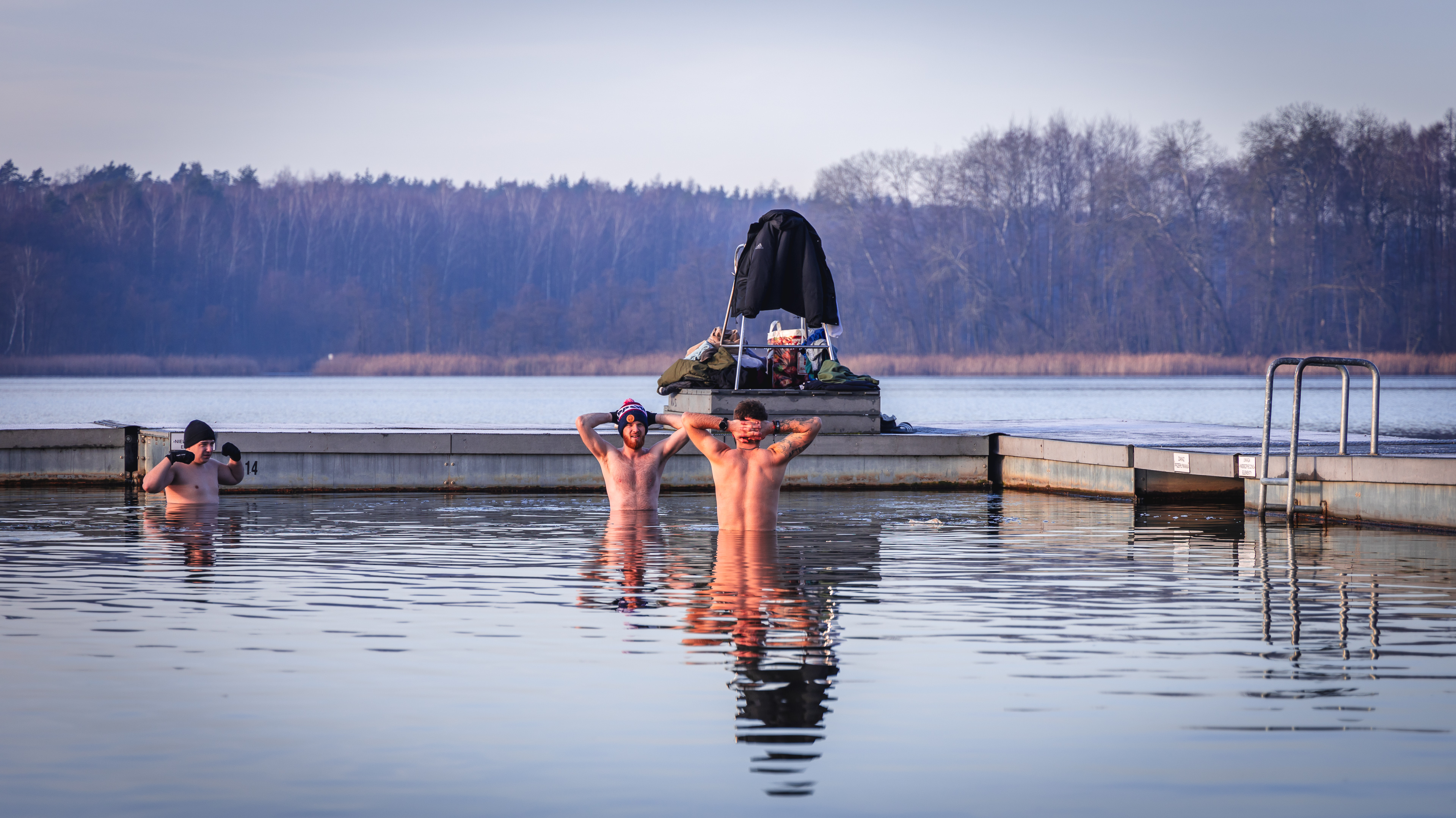 Zdjęcie przedstawia grupę trzech mężczyzn morsujących w jeziorze